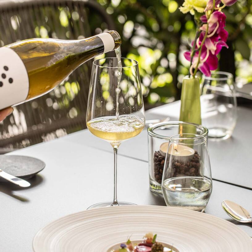 Wein einschenken an gedecktem Tisch im Aussenbereich