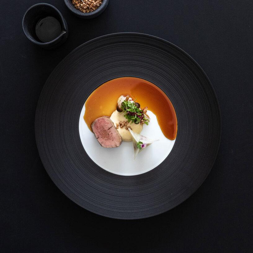 Gericht angerichtet auf schwarzem Teller